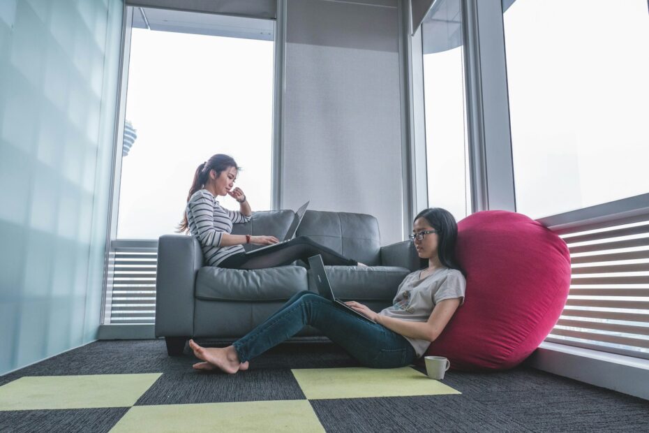 two women sitting on sofa and floor inside gray painted room