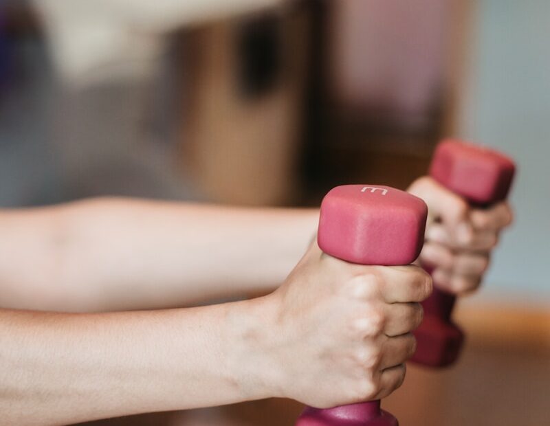 person holding pink and white dumbbells